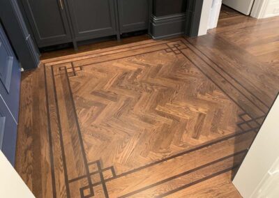 Select White Oak and Herringbone motif with 3 board border inlay. Stained in place.